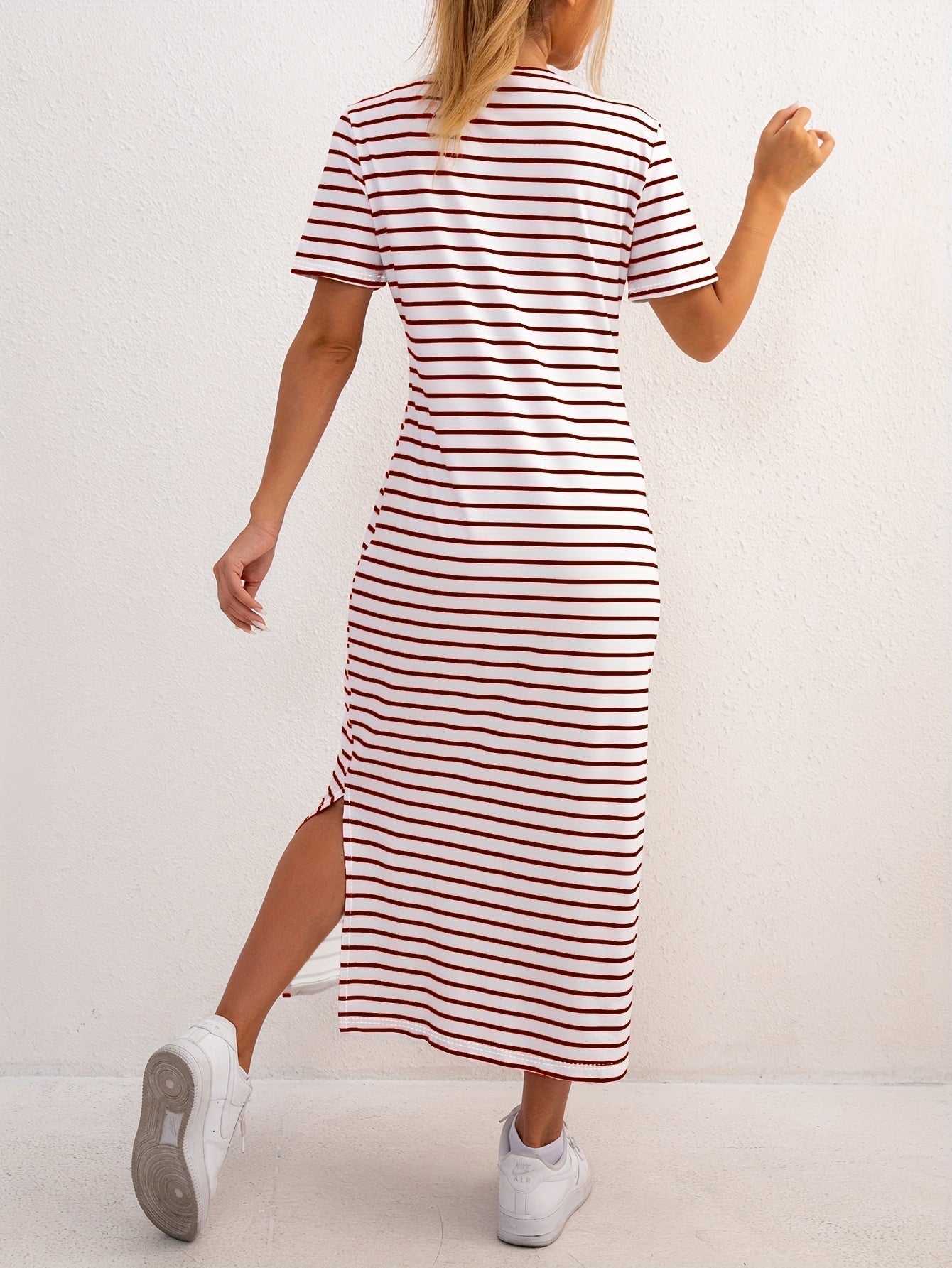 Fashionable woman accessorizing the red striped jersey midi dress with a handbag and sunglasses, ready for a day out.