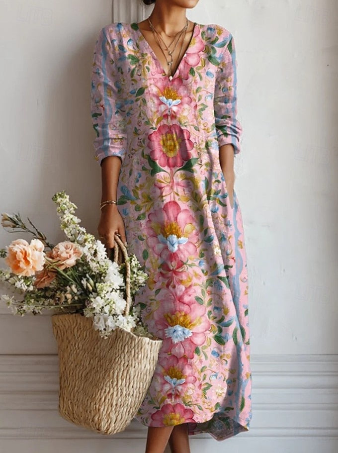 Front view of the Keira floral comfort dress in a vibrant blue pattern, worn by a smiling model in a sunny outdoor setting.