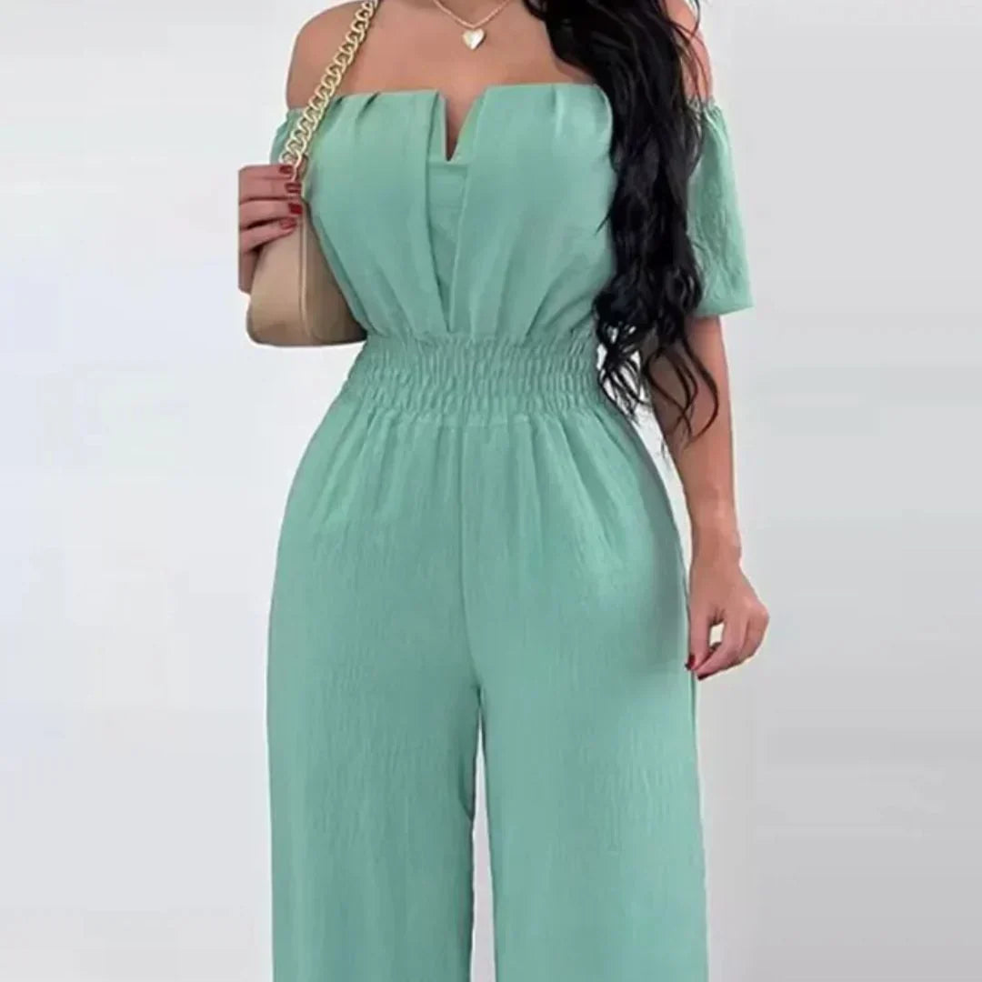 Side profile of a woman showcasing the flowing fabric and straight leg design of the chic off-shoulder jumpsuit.