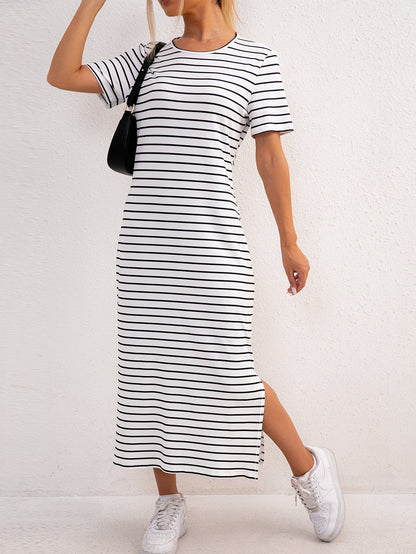 Front view of model wearing a white and blue striped jersey midi dress, standing casually outdoors.