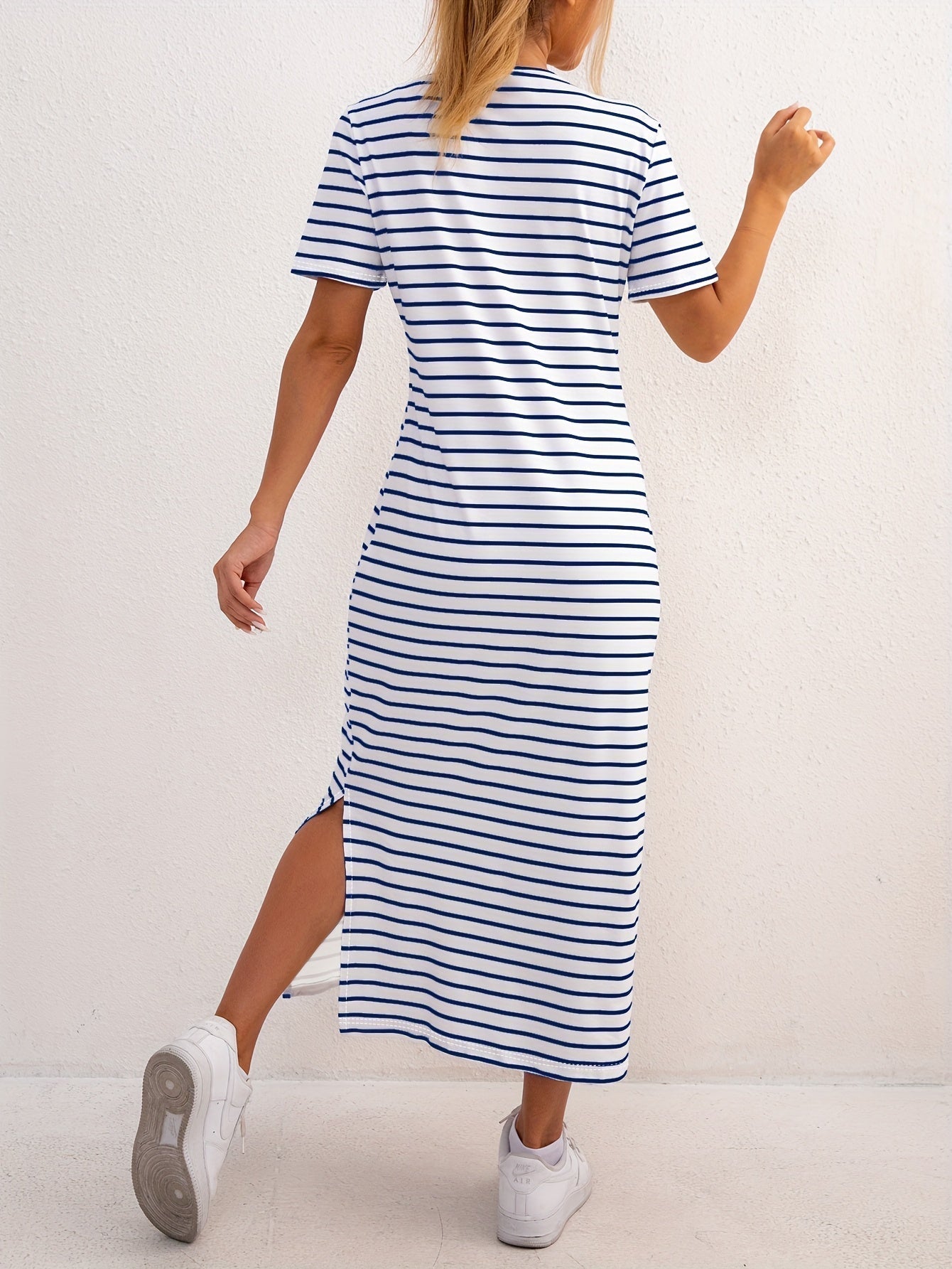 Model in a navy blue striped jersey midi dress, styled with white sneakers, looking relaxed and chic.