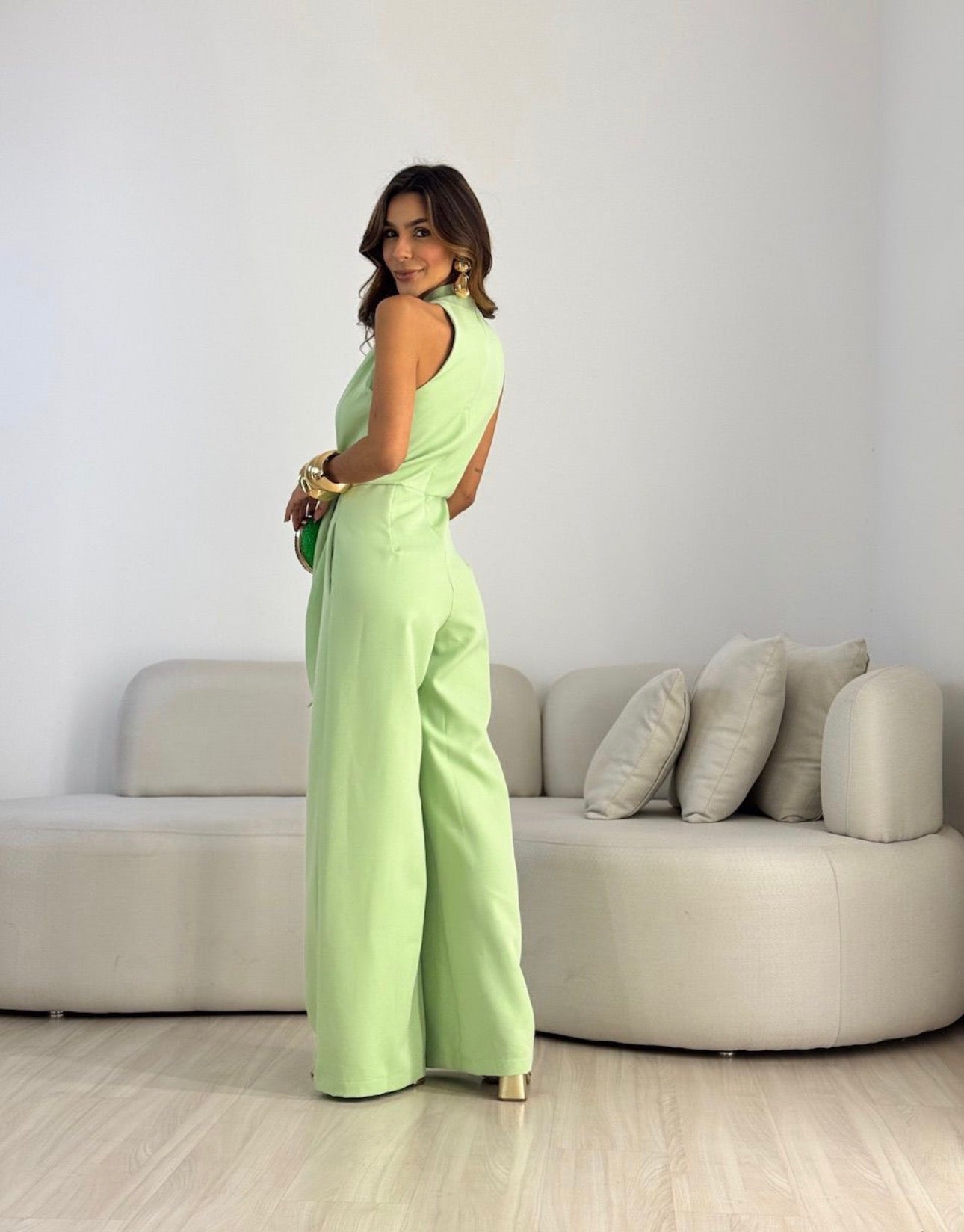 Side profile of a woman wearing the beige wide-leg halterneck jumpsuit, showcasing its flowing silhouette.