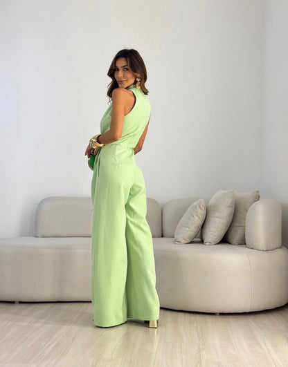 Side profile of a woman wearing the beige wide-leg halterneck jumpsuit, showcasing its flowing silhouette.