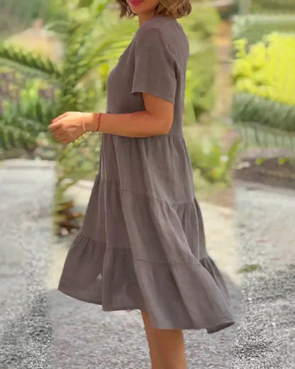 Lifestyle shot of the Esmée flowy boho midi dress in a soft pink, worn outdoors in a sunny park setting.