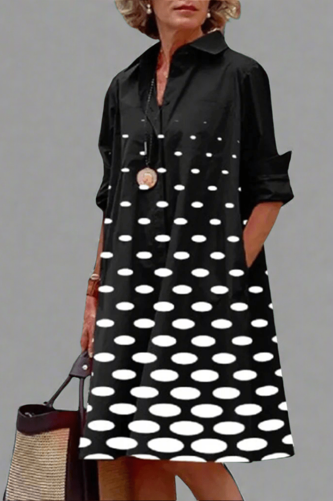 Front view of a woman wearing a black polka dot midi dress, showcasing its relaxed fit and elegant drape against a bright background.