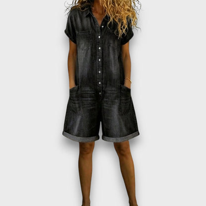 Side profile of a woman in a dark blue denim jumpsuit, showcasing the flattering drape and balanced silhouette.