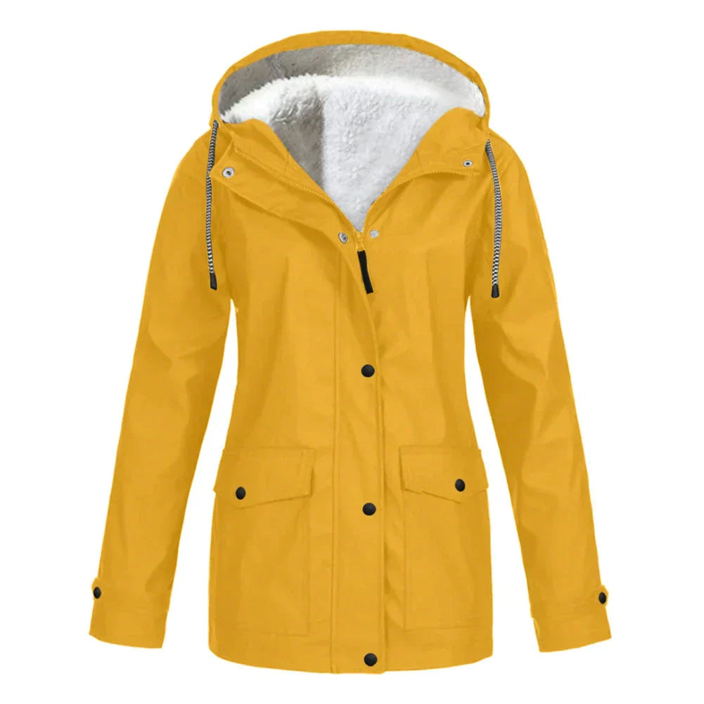 A woman in a red warm lined rain jacket enjoying a walk through a city street during light rain.