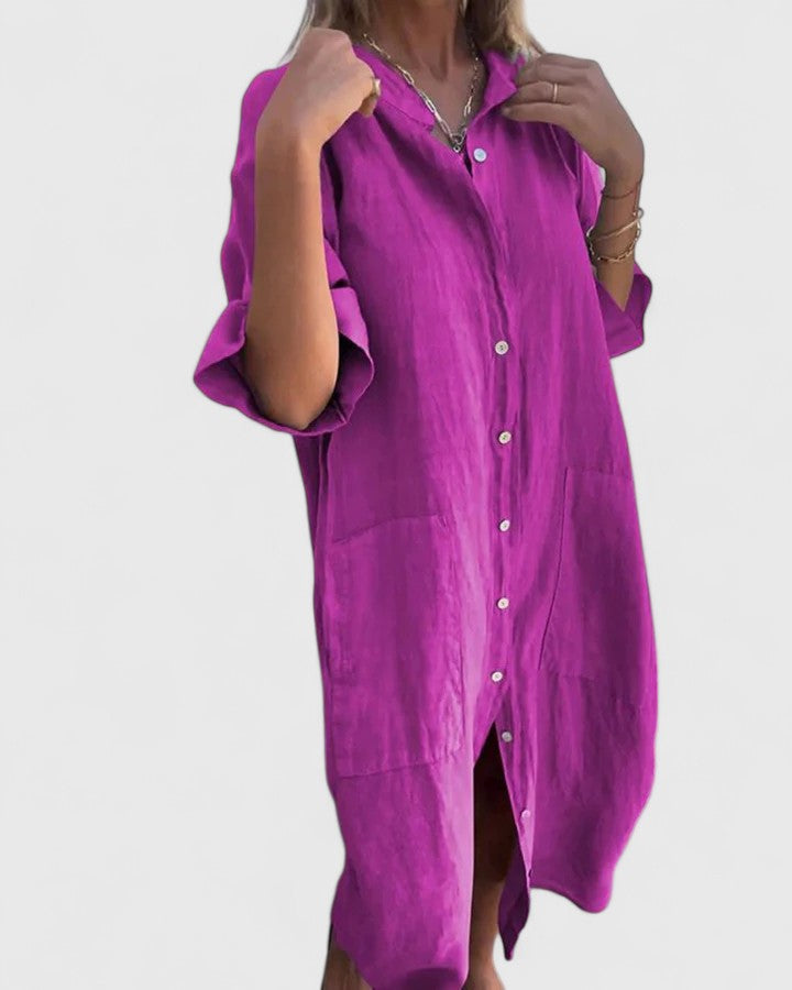 Woman posing in the Mila relaxed dress in a rich purple, highlighting the practical side pockets.