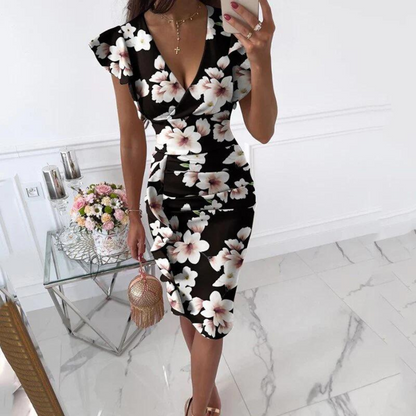 Front view of a woman joyfully posing in a vibrant floral V-neck dress outdoors on a sunny day.