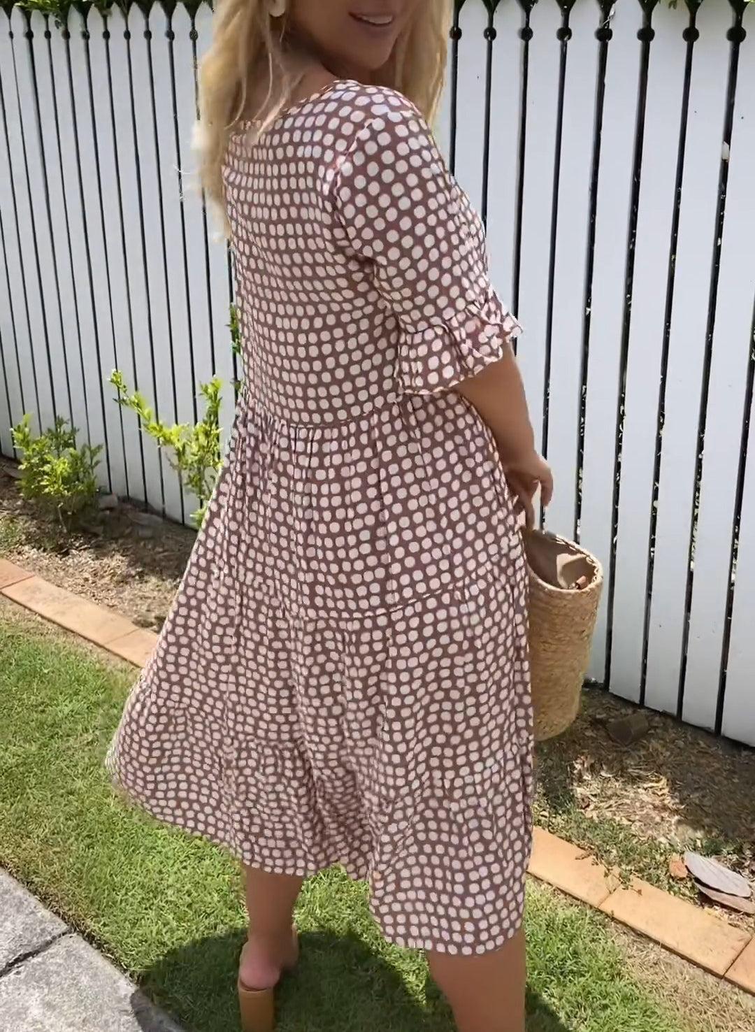 A woman laughing while twirling in the brown bohemian midi dress, showing its airy movement.