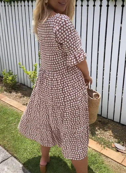 A woman laughing while twirling in the brown bohemian midi dress, showing its airy movement.