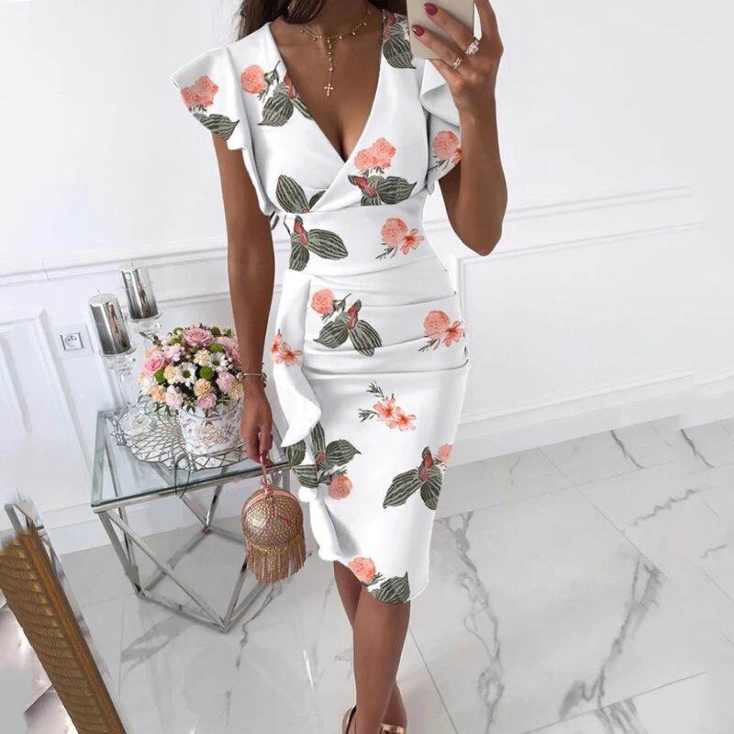 Lifestyle shot of the floral V-neck dress paired with summer sandals and a straw bag in a park setting.