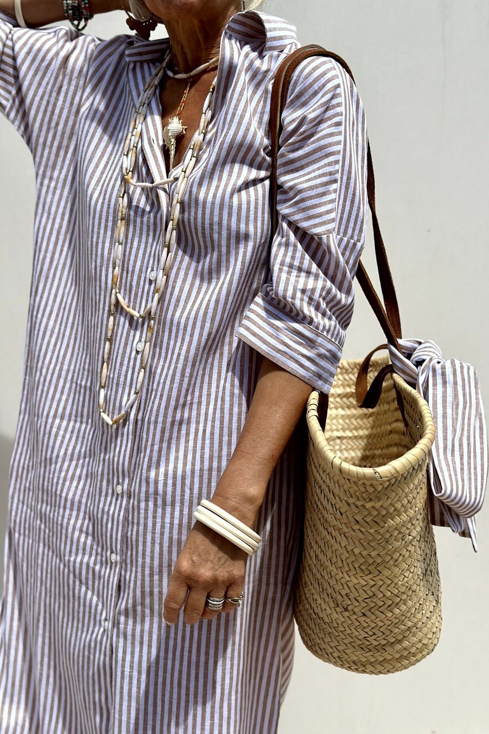Model accessorizing the Paloma striped dress with sandals and a belt, demonstrating a more defined look.