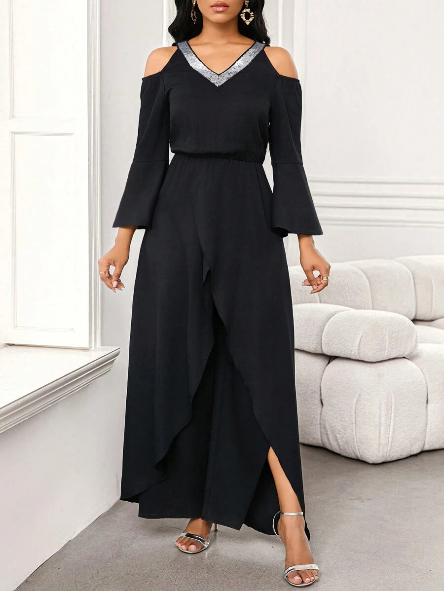 Full body view of a woman confidently posing in the black Zarae elegant jumpsuit, showcasing its loose fit and graceful sleeves.