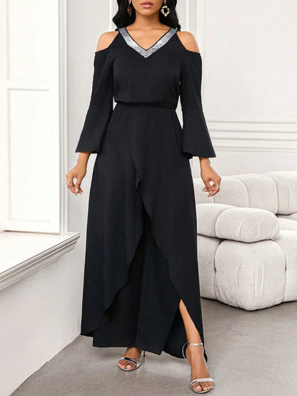 Full body view of a woman confidently posing in the black Zarae elegant jumpsuit, showcasing its loose fit and graceful sleeves.