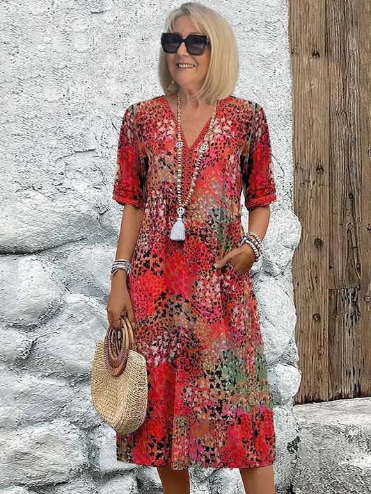 Front view of a woman smiling in a colorful vibrant midi dress with a floral pattern, perfect for summer.