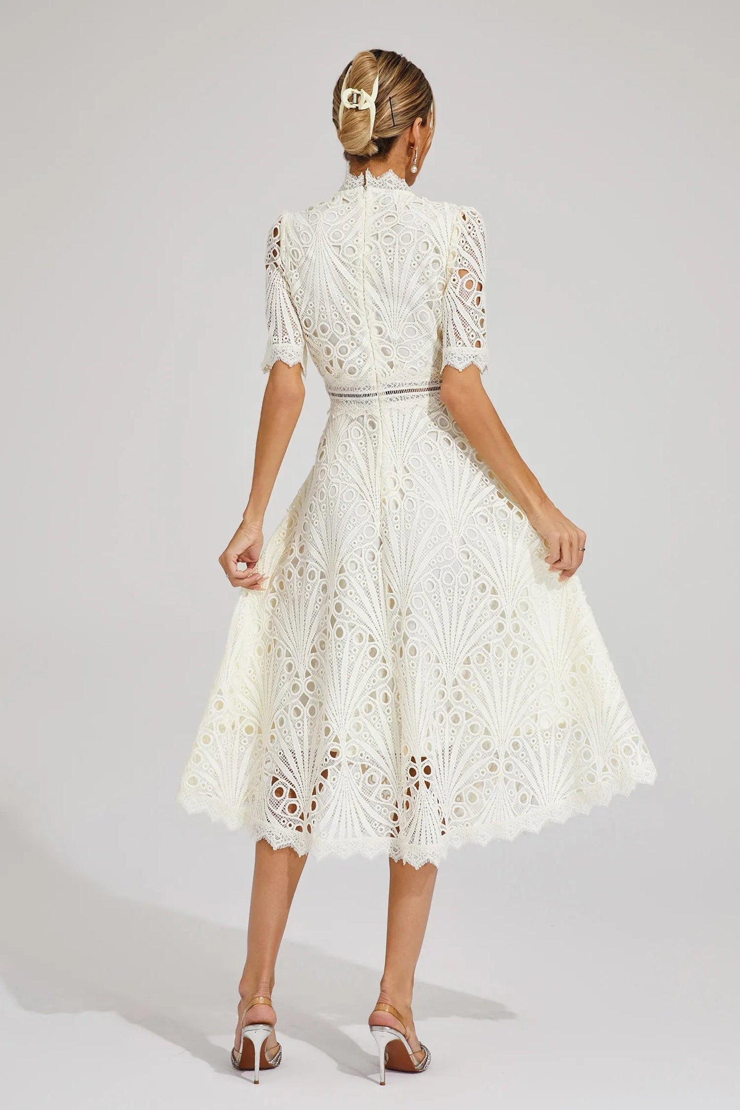 Detail shot of the intricate cut-out pattern on the delicate lace midi dress fabric.