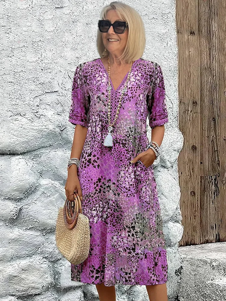 Woman sitting relaxed on a patio, enjoying a drink while wearing the stylish and colorful vibrant midi dress.