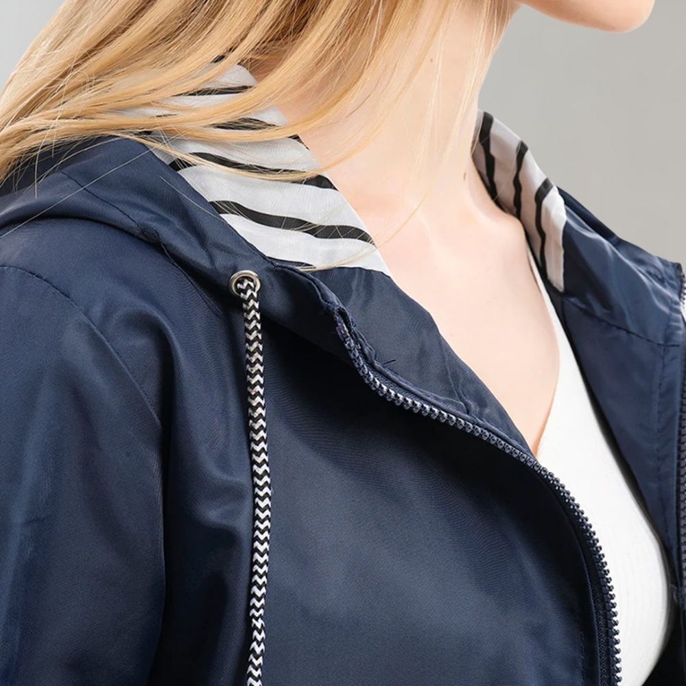 Lifestyle shot of a woman in a navy fashionable waterproof jacket, paired with smart casual attire for an urban look.